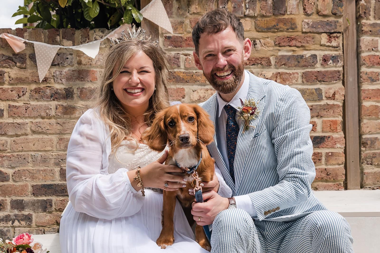 A bride, groom and their dog smile at the camera at a wedding in Berkhamsted