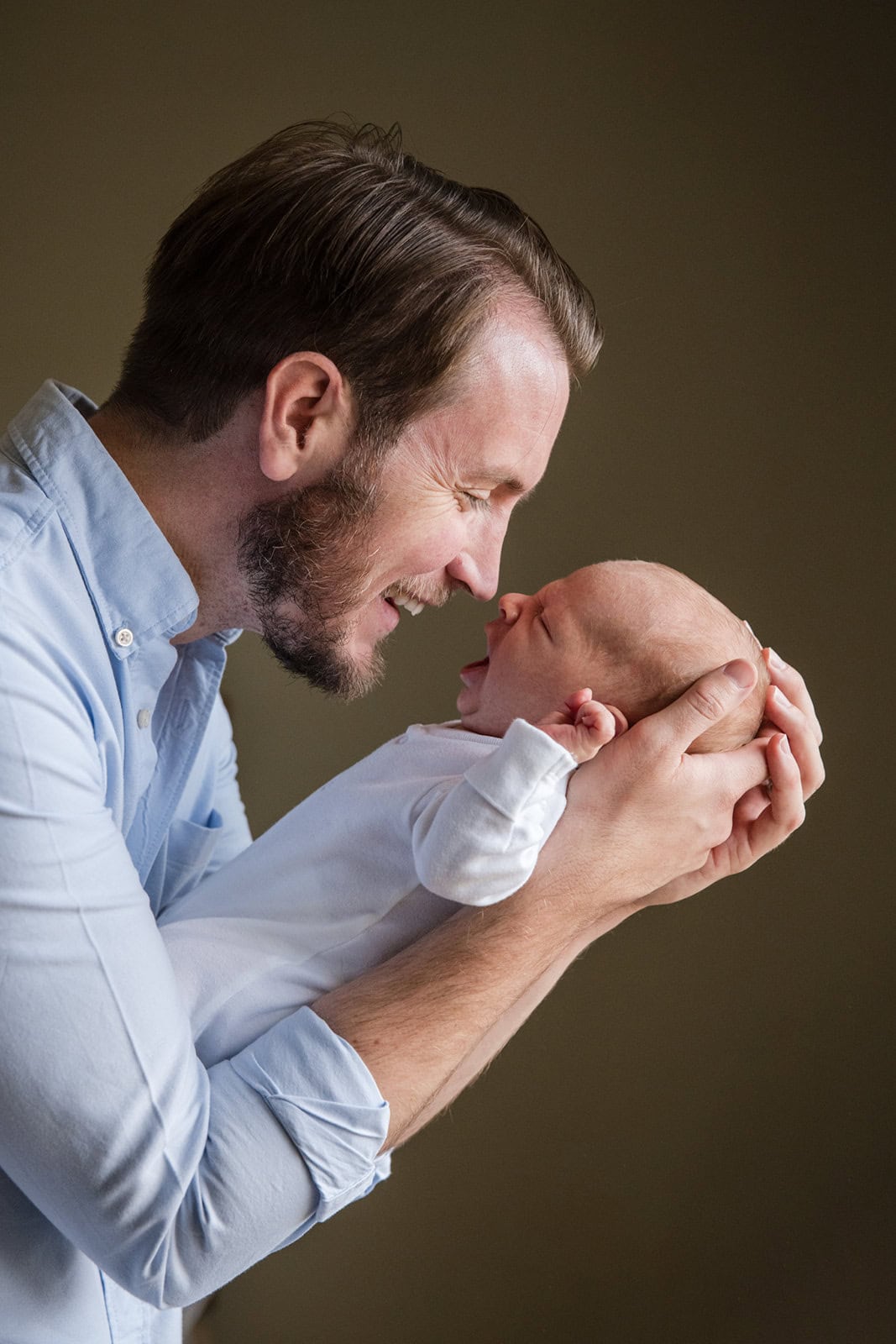 New dad smiles while touching noses with his new son during a newborn photoshoot